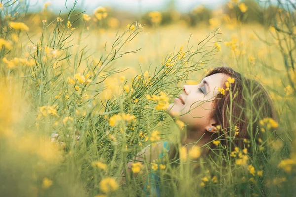 美しいロマンチックな女の子が咲く菜の花畑自然を楽しむ若いエレガントな女性が歩く花から見上げるきれいな女性の顔 — ストック写真