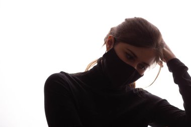 Beyaz arka planda koruyucu maskeli, kafası başının üstünde duran genç, bıkkın bir kadının silueti.