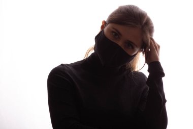 Beyaz arka planda koruyucu maskeli, kafası başının üstünde duran genç, bıkkın bir kadının silueti.