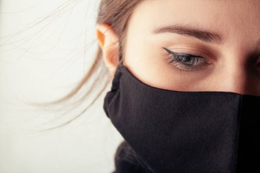 Siyah stil maskeli üzgün genç bir kadının yüzü. Gözleri aşağıda, moda ve 2020 yılında karantina ve salgın altında.,