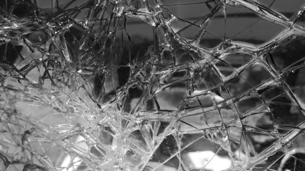 The broken windshield of the car. Glass splinter. An accident with the car. Dangerous traffic accident. Road accident. Glass background. Black and white photography.