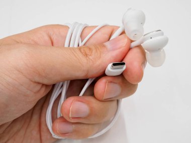 Bir çift Usb-C kulaklığı beyaz bir gruba karşı tutarak.