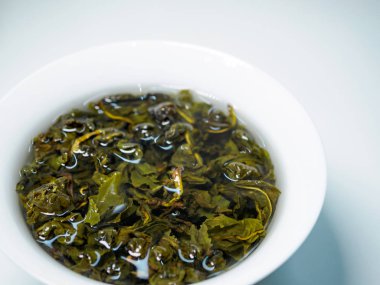 Beyaz arka planda porselen bir fincanda demlenmiş Çin yeşil oolong çayı.