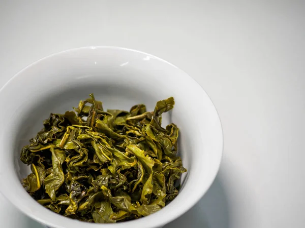 Islak ve nemli Çin yeşil oolong çay yaprakları porselen bir fincanda 