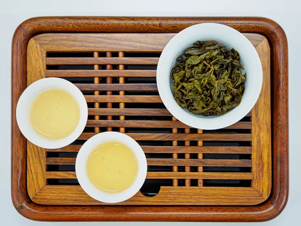 Visão aérea de xícaras de chá verde oolong e folhas de chá em uma bandeja de madeira — Fotografia de Stock