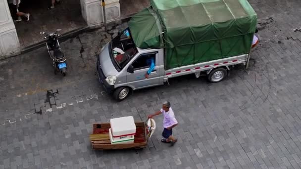 3月2 2019 中高年アジアの中国人男性 配達労働者の空中パンショット古い都市の通りを通ってロードされたトロリーを押す海口 — ストック動画