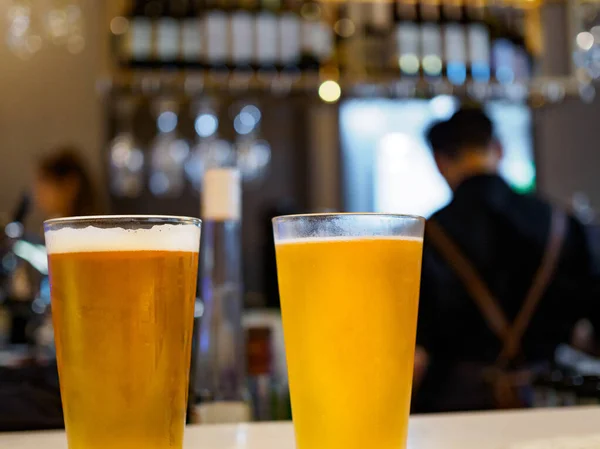 Two pint glasses of beer / lager/ ale at a bar counter in a pub