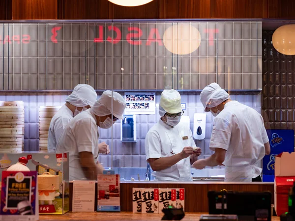 SINGAPORE 23 MAR 2020 Şefler maske takarak Çin restoranının açık mutfağında buğulanmış hamur köftesi yapıyorlar..