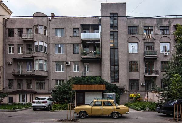 Κίτρινο παλιό αυτοκίνητο μπροστά constructivist κτίριο — Φωτογραφία Αρχείου
