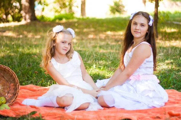 Две Девушки Белых Платьях Играют Оранжевом Пикнике Корзиной Пикника Парке — стоковое фото