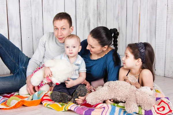 美丽的微笑的家庭躺在地板上 玩具铺在五彩缤纷的毯子上 室内摄影 — 图库照片
