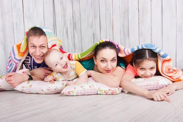 幸福的一家人躺在地板上 盖着五颜六色的毯子 光芒四射 室内照片拍摄 空白处 空白处 — 图库照片