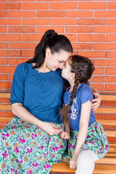 Mother Daughter Similar Clothes Hug Sit Bench Front Red Brick — Stock Photo, Image