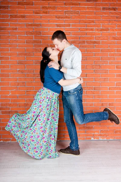 赤レンガの壁の前で若いカップルのキス 室内写真撮影 — ストック写真