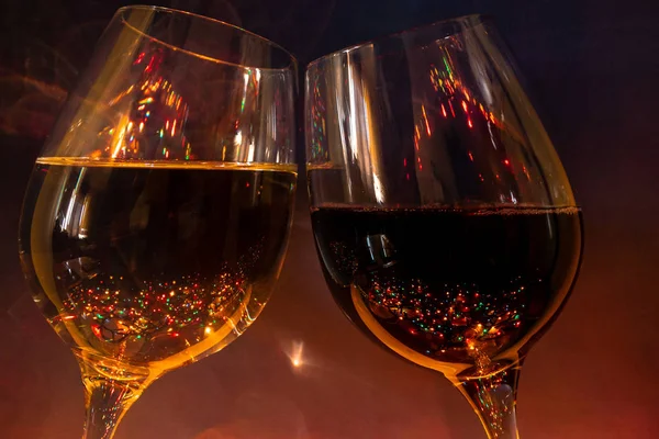 a glass of champagne and a glass of wine on a dark purple background