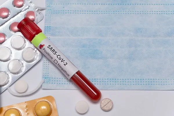 Blood positive test to coronavirus. Medical reseach, test-tube with blood, medical mask, pills. Coronavirus outbreak and influenza. 2019-nCoV, covid-19, sars. High quality photo.
