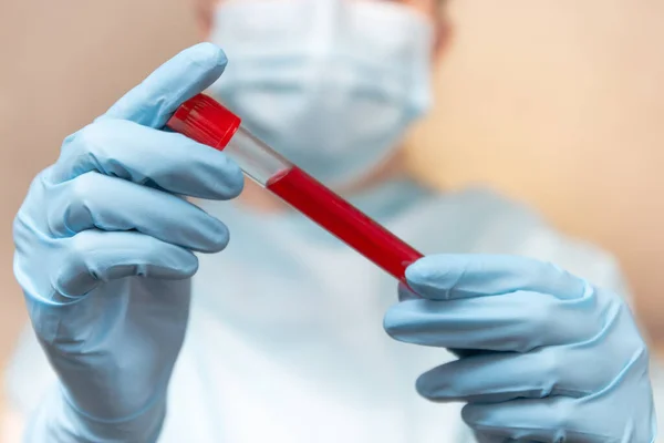 Coronavirus blood test. Doctor in protective suit, medical mask and latex gloves holds a test tube with blood. — Stock Photo, Image