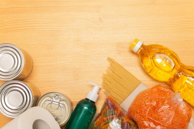 Yemek dağıtım servisi. Karantina sırasında internetten ürün alın. Ahşap arka planda sağlıklı yemek ve antiseptik. Ayçiçeği yağı, domates, makarna, ekmek, mercimek, konserve yiyecek, tuvalet kağıdı, dezenfektan.