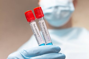 Coronavirus aşısı, pozitif ve negatif. Koruyucu giysili doktor, tıbbi maske ve lateks eldivenler aşı ile test tüpleri tutuyor.. 