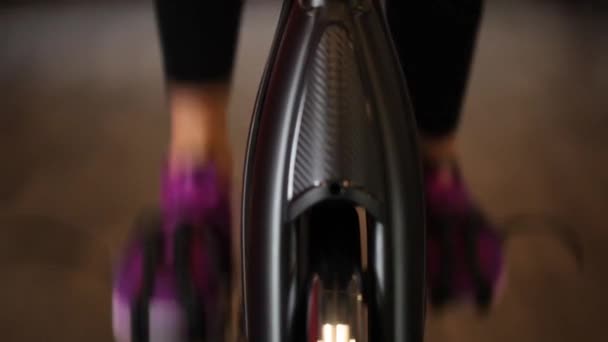 現代の暗いジムで運動器具を使用して運動の女の子 自転車のペダルのフィットネス ペダルの上の女性の足を閉じる 健康的なライフスタイルとスポーツの概念 サイクル中の女性 — ストック動画