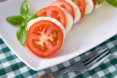 Mozzarella peyniri, domates ve fesleğen rustik ahşap masa üzerinde Caprese salatası