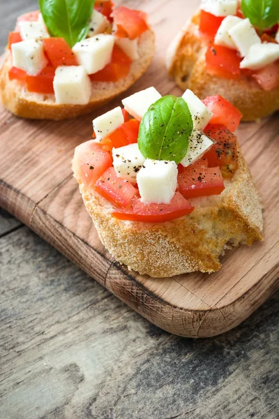 Caprese salad bruschettas on wooden table — Stock Photo, Image