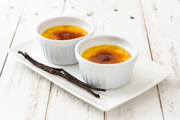 Postre francés tradicional de la creme brulee con el azúcar caramelizado en la tapa, en la tabla de madera blanca —  Fotos de Stock