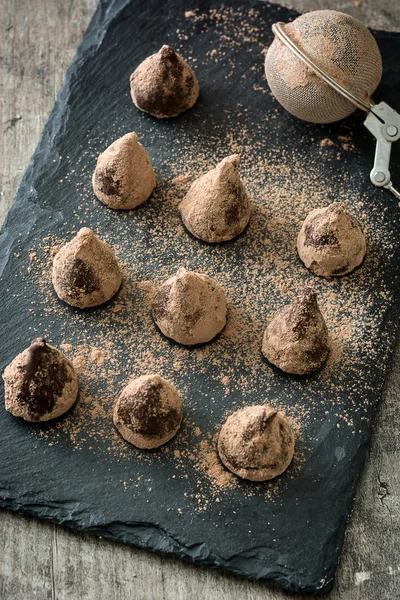 Homemade chocolate truffles on slate plate and wooden table — Stock fotografie