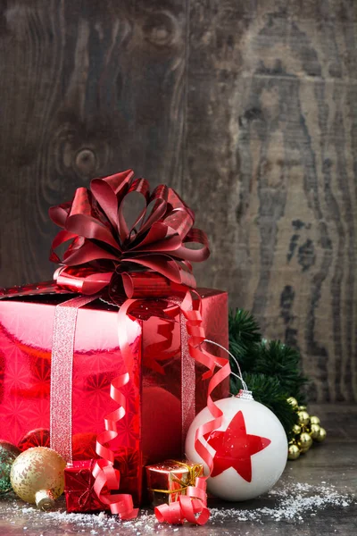 Red gift box and Christmas balls on wooden background — Stock Photo, Image