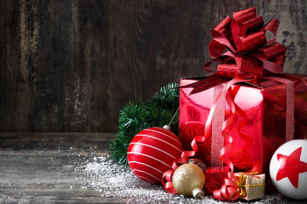 Červená dárková krabička a vánoční koule na dřevěné pozadí — Stock fotografie