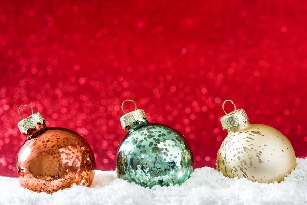 Boules de Noël sur fond de neige et de paillettes rouges — Photo