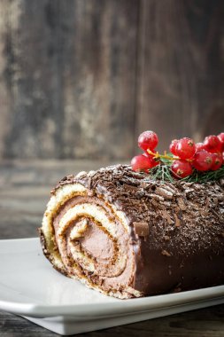 Ahşap arka plan üzerinde kırmızı kuş üzümü ile çikolata yule log pasta