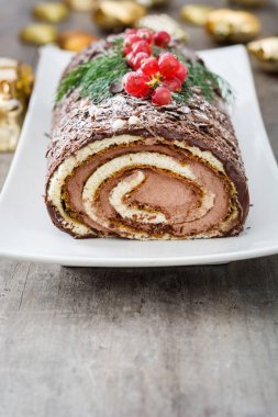 Ahşap arka plan üzerinde kırmızı kuş üzümü ile çikolata yule log pasta