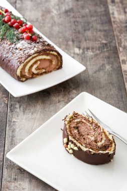 Ahşap arka plan üzerinde kırmızı kuş üzümü ile çikolata yule log pasta