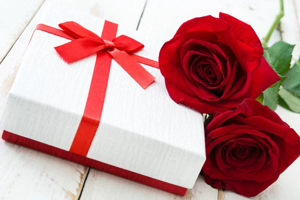 Cutie cadou alb și trandafiri pe masă albă din lemn . — Fotografie, imagine de stoc