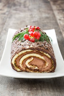 Çikolata yule log Noel Kek ile ahşap arka plan üzerinde kırmızı kuş üzümü