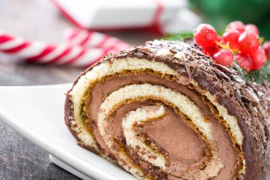 Çikolata yule log Noel Kek ile ahşap arka plan üzerinde kırmızı kuş üzümü