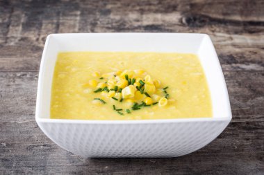Ahşap masa üzerinde beyaz kase mısır çorbası