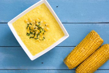 Mavi ahşap zemin üzerine kase mısır çorbası