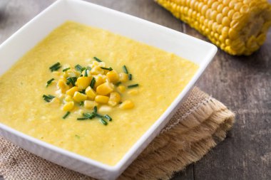 Ahşap arka plan üzerinde beyaz kase mısır çorbası