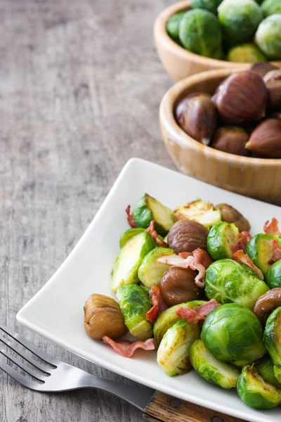 Choux de Bruxelles avec châtaignes et bacon sur table en bois — Photo