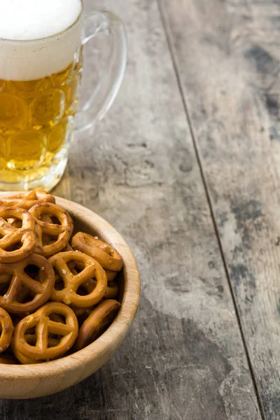 Pretzels en tazón y cerveza en mesa de madera —  Fotos de Stock