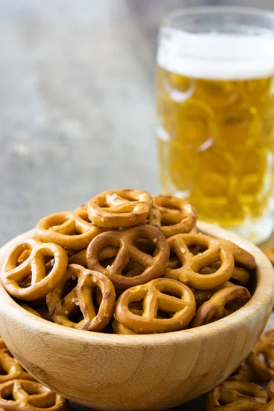 Pretzels en tazón y cerveza en mesa de madera —  Fotos de Stock