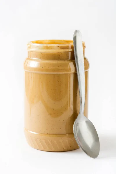 Сливочное арахисовое масло и ложка на белом фоне — стоковое фото