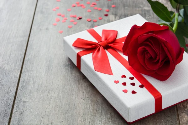 Geschenkbox und rote Rose auf hölzernem Hintergrund. — Stockfoto