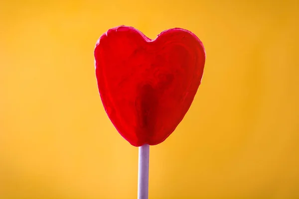 Piruleta roja con forma de corazón sobre fondo amarillo. Concepto de amor. Día de San Valentín . —  Fotos de Stock