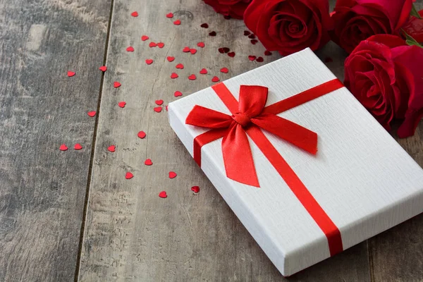 Geschenkbox und rote Rose auf hölzernem Hintergrund. — Stockfoto