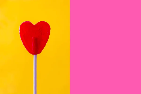 Röd lollipop med hjärta form på gula och rosa bakgrund. Kärlek-konceptet. Alla hjärtans dag. — Stockfoto
