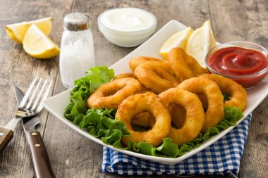 Marul ve ahşap zemin üzerine ketçap ile kızarmış kalamar halkaları