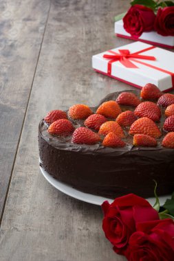 Sevgililer günü veya ahşap zemin üzerine anneler günü için kalp şeklinde pasta ve kırmızı gül